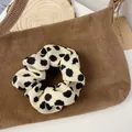 Close-up of a vintage black polka dot scrunchie on a rustic wooden decorative plate - Beige Dot
