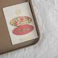 Detail of two floral fabric hair clips with daisy embroidery on white card - Pink Series