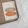 Gros plan de barrettes à fleurs brodées à la main sur une carte de présentation - 2 Pièces/Ensemble / Série Orange