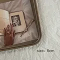 Vue détaillée d'une barrette dorée de 6cm ornée de strass brillants sur un livre rétro - Doré / 6cm