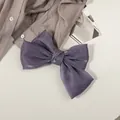 Détail de la texture d'un grand nœud papillon en satin nacré violet sur un tissu - Violet Profond