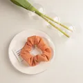 Détail du grand chouchou orange avec texture de tissu plissé sur une assiette minimaliste - Texturé Orange