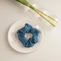 Vue détaillée d'un chouchou bleu marine en tissu texturé sur une assiette blanche - Texturé Bleu Foncé