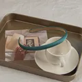 Detail of peacock green satin headband showing non-slip lining on a gold tray - Peacock Green