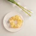 Détail du chouchou jaune clair à texture bulles sur plateau blanc avec décor végétal - Texturé Jaune Lait