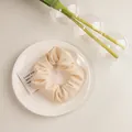 Vue détaillée du chouchou blanc crème en tissu gaufré posé sur une assiette en céramique - Texturé Crème