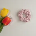Détail d'un chouchou rose avec motifs de fleurs blanches et texture de tissu doux - Rose