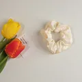 Détail d'un chouchou floral jaune clair avec motif marguerite blanche sur tissu texturé - Fleur blanc cassé