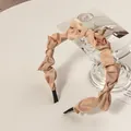 Detail view of champagne satin ruffled headband with soft silk texture and protective end caps - Khaki