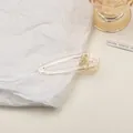 Detailaufnahme einer klaren Acryl-Haarklammer in Tropfenform mit Metallfeder - Groß / Champagner