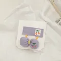 Détail d'accessoires de cheveux violets brodés de cerises avec un nœud et une pince clip - Violet