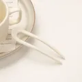 Detail einer minimalistischen cremeweißen U-förmigen Haarnadel für Frisuren - Milchweiß