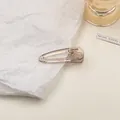 Detailed view of a translucent amber water-drop hair clip on a minimalist white backdrop - Small / Gray Brown