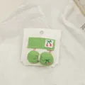 Detailed macro view of green fabric hair clips with pink cherry embroidery on white background - Green