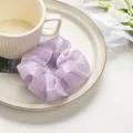 Detail of light purple organza hair scrunchie with soft satin texture on ceramic plate - Violet