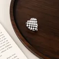 Detailed view of a mini heart-shaped checkerboard hair claw clip on a rustic wooden tray - Black and White Grid