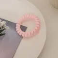 Nahaufnahme eines rosa Spiralgummis in Telefonkabel-Optik auf einem dekorativen Tablett - Zartrosa