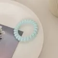 Detailansicht eines hellblauen Spiralhaargummis auf einem dekorativen weißen Teller - Frisches Blau