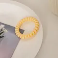 Nahaufnahme des cremiegelben Spiralgummis auf weißem Keramikteller mit Tulpenkarte - Zartgelb