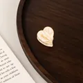 Macro view of mini heart-shaped acetate hair claw clip on vintage wooden background - Creamy Beige