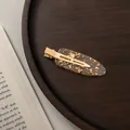 Detailed view of duckbill hair clip with golden metal base and gold foil resin texture - Large / Transparent Gold Foil