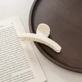Pinza de pelo grande color crema mate sobre una bandeja de madera y un libro - Blanco Leche