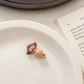 Detail of cartoon character hair clip with bead on white tray with book background - Brown Hair Man