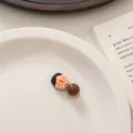 Close-up of a cute cartoon character hair clip on an ivory plate with vintage book - Black Hair Moustache