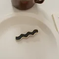 Nahaufnahme einer Haarklammer im französischen Wellendesign in Schwarz und Creme-Weiß - Welle-Schwarz