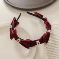 Primer plano de diadema de terciopelo granate con perlas sobre un libro antiguo - Burdeos
