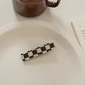 Nahaufnahme der schwarz-weißen Schachbrett-Haarklammer auf weißem Teller mit Kaffee - Schachbrett-Rechteckig