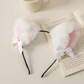 Detail of plush cat ear headband with white bows and bells resting on an open book - White