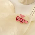 Gros plan d'une pince à cheveux cerise rose en forme de cœur avec un visage souriant doux - #1 Smiley Pink Cherry