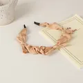Close-up of beige pleated silk headband with soft black cushions on a minimalist table - 27# Triple Bow Style
