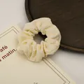 Detail of beige corduroy scrunchie texture on a wooden tray with soft lighting - Milky Yellow