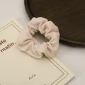 Close-up of cream corduroy hair scrunchie with soft ribbed texture and pleated design - Light Pink