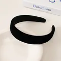 Detail of a padded black velvet headband resting on a white ceramic plate and book - Black