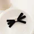 Dettaglio del fermaglio a fiocco in velluto con strass centrale su un piatto bianco - Strass Ovale