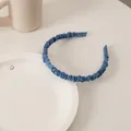 Dettaglio del cerchietto a pieghe blu Klein in raso su un set da tavola bianco - Plissettato Fine Blu Scuro