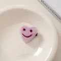 Nahaufnahme einer Haarspange aus rosa Filzherz mit besticktem Lächeln auf einem Teller - 14# Herz Smile-Violett