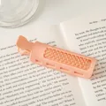 Detail eines pfirsichfarbenen Haarwurzelclips mit feinen Zähnen vor einem Lifestyle-Hintergrund - Orange
