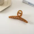 Nahaufnahme der bernsteinfarbenen Haarklammer mit Kreuzdesign vor minimalistischem Hintergrund - Braun