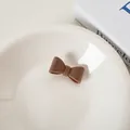 Dunkelbraune Samt-Haarspange mit Schleife auf einem weißen Keramikteller präsentiert - Braun