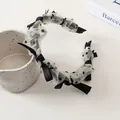 Détail d'un serre-tête en résille à pois avec nœud en satin noir de style vintage - Style Maille Beige à Pois