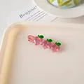 Detalle de tres melocotones rosas de acrílico con hojas verdes en un clip de pelo metal - Pinza Pico de Pato Melocotones
