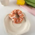 Detail eines warmen orangefarbenen Scrunchie mit weißen Gänseblümchenmustern - 2# Orange