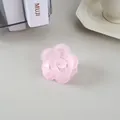 Vue macro d'une pince à cheveux fleur rose mat sur un fond de bureau minimaliste - Mauve Gelée
