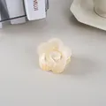 Détail d'une pince à cheveux fleurie crème mate dans un décor de bureau minimaliste - Jaune Gelée