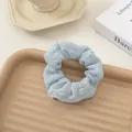 Light blue seersucker scrunchie with pleated texture on a decorative tray - Blue