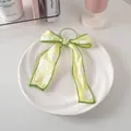 Dettaglio di un elastico per capelli con fiocco verde a pois su un piatto di ceramica bianco - Elastico Per Capelli A Nastro N. 34 - Verde